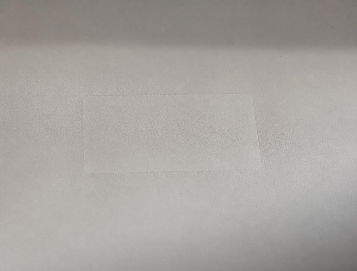 Surface de papier mat portant l’empreinte discrète d’un objet retiré.